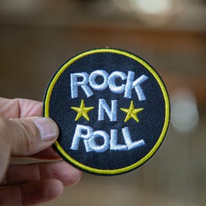 Könnte beinhalten: Eine weiße Keramik-Tasse mit schwarzem Henkel und dem Text "But First, Coffee" in schwarzer, handschriftlicher Schrift. Die Tasse steht auf einer weißen Oberfläche.