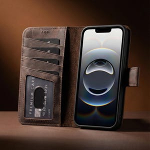 Könnte beinhalten: Braune Leder-Handyhülle mit Kartenfächern und Magnetverschluss. Die Hülle enthält ein schwarzes Smartphone mit hellem Bildschirm. Die Kartenfächer zeigen eine Kreditkarte und andere Karten. Die Hülle ist geöffnet.