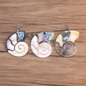 May include: Three nautilus shell pendants featuring inlaid iridescent abalone shell segments and smooth mother-of-pearl sections. Each pendant is shaped like a spiral shell and includes a silver-toned metal bail at the top for attachment.