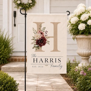 May include: A rectangular garden flag featuring a large beige letter H decorated with a floral arrangement of burgundy, pink, and white flowers. Below the letter, the text reads The HARRIS Family and EST. 2024 in black serif and script fonts.