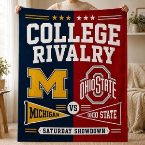 May include: A rectangular throw blanket split vertically into navy blue and red sections. The text COLLEGE RIVALRY appears at the top. It features a yellow block M, the Ohio State logo, two pennants labeled MICHIGAN and OHIO STATE, and the text SATURDAY SHOWDOWN at the bottom.
