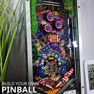 Peut inclure: Maquette de flipper colorée avec un thème patriotique, ornée d'étoiles et de rayures rouges, blanches et bleues. Le texte "BUILD YOUR OWN PINBALL MACHINE" est affiché. Le modèle est à l'échelle 1:4.