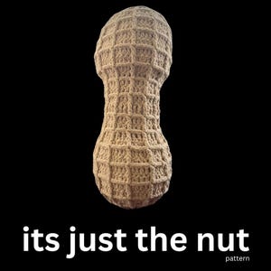 May include: A beige crocheted peanut shape against a black background. The peanut is made with a textured stitch pattern. The text "its just the nut" is at the bottom of the image, with "pattern" below it.