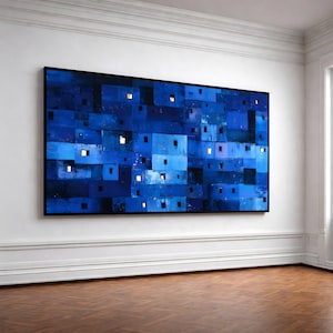 以下が含まれることがあります： 大きな額入りの抽象画。青と濃い青の長方形の形がモザイク状に配置され、小さな正方形の窓が光っています。絵は白い壁に掛けられ、寄木張りの床の上にあります。