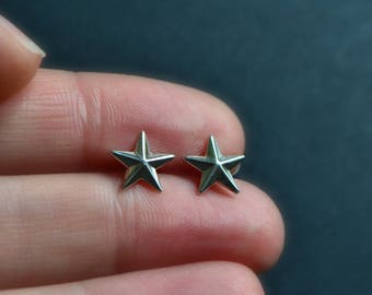 May include: A pair of silver star-shaped stud earrings.
