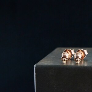 May include: A pair of rose gold skull stud earrings. The earrings are small and delicate, and they are perfect for adding a touch of edgy style to any outfit.