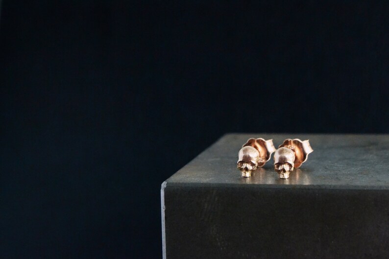May include: A pair of rose gold skull stud earrings. The earrings are small and delicate, and they are perfect for adding a touch of edgy style to any outfit.