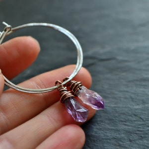 May include: Silver hoop earrings with two amethyst crystal drops wrapped in copper wire.
