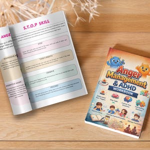 Op de afbeelding: Twee boeken op een houten oppervlak. Eén is open en toont tekst over vaardigheden voor woedebeheersing. De andere is een werkboek getiteld "Anger Management & ADHD Workbook" met cartoonillustraties en tekst.