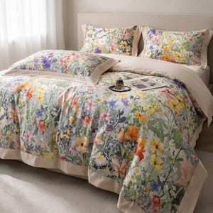 Può includere: Un set di biancheria da letto a fantasia floreale, composto da un copripiumino e federe. Il design presenta una stampa in stile acquerello di fiori colorati nei toni del giallo, arancione, viola e rosa su sfondo grigio chiaro. Bordi beige.