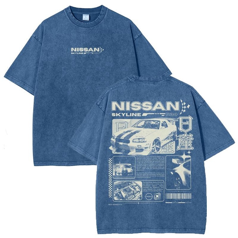 Puede incluir: Camiseta azul de manga corta con efecto lavado. La parte delantera presenta el texto "NISSAN SKYLINE" en blanco. La parte trasera muestra un gr&aacute;fico de coche blanco con el texto "NISSAN SKYLINE R34" y texto japon&eacute;s.