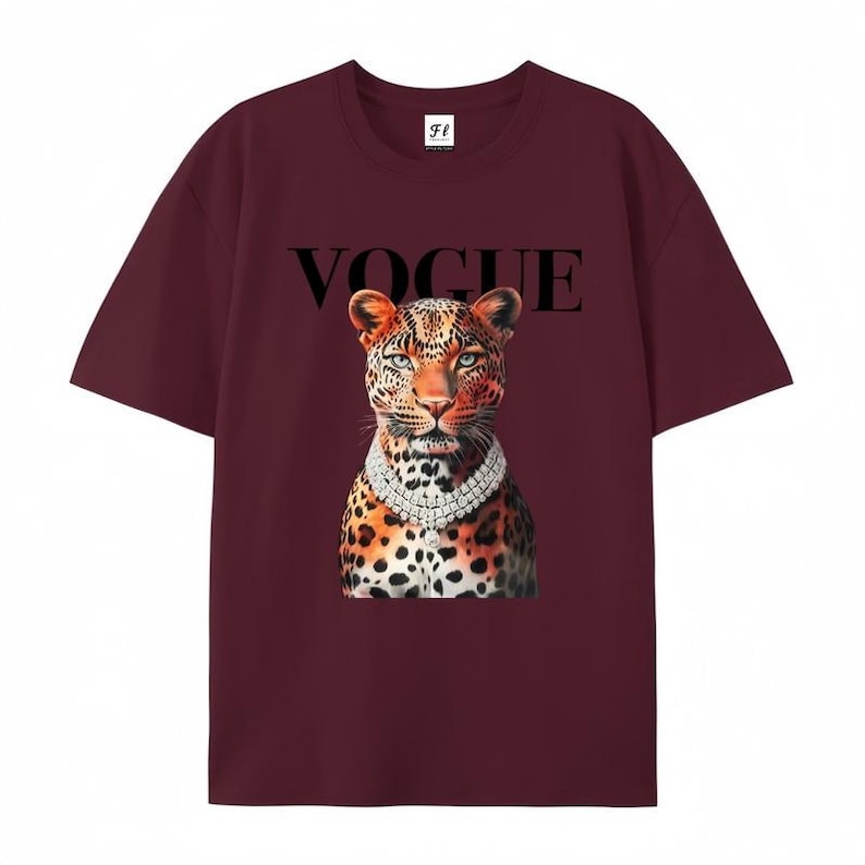 May include: Burgundy t-shirt featuring a leopard illustration wearing a diamond necklace, with the word "VOGUE" above the leopard's head. The shirt has short sleeves and a crew neck.