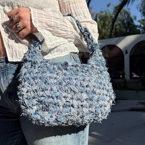 Peut inclure: Une tasse en céramique blanche avec une anse noire et le texte "But First, Coffee" en gras noir. La tasse est posée sur un fond neutre, soulignant son design simple.