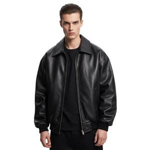 Puede incluir: Chaqueta de cuero negra con cuello clásico y cierre de cremallera. La chaqueta tiene un diseño tipo bomber con puños y dobladillo acanalados. El modelo lleva una camiseta negra debajo. Prenda de abrigo versátil.