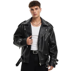 Puede incluir: Chaqueta de cuero negra con solapas anchas, cremallera asimétrica y múltiples cremalleras y hebillas plateadas. La chaqueta, de estilo motero, tiene cinturón en la cintura y correas en las mangas.