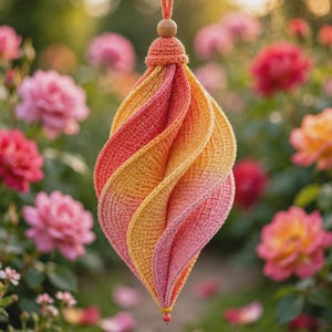 May include: A hanging crochet ornament featuring a spiralling, teardrop-shaped design with a gradient of warm yellow, orange, and pink hues. The piece is topped with a small wooden bead and a matching crochet cap, finished with a tiny bead at the base.