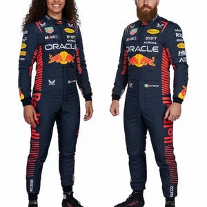 May include: Two navy blue racing suits with red and yellow detailing. Each suit displays sponsor logos such as "Oracle" and "Bybit," and a Red Bull logo. The suits have long sleeves and are paired with black boots. One suit is worn by a woman, the other by a man.
