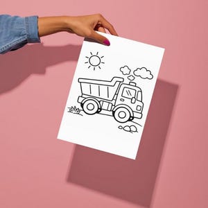 Op de afbeelding: Een zwart-wit lijntekening van een dumper, zon, wolken en gras op wit papier. De afbeelding wordt vastgehouden door een persoon met een roze achtergrond.