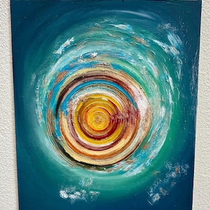 Könnte beinhalten: Abstrakte Acrylmalerei auf Leinwand. Das Kunstwerk zeigt ein zentrales Spiraldesign mit konzentrischen Ringen in Gelb-, Orange-, Rot-, Braun- und Blautönen. Der Hintergrund ist tief türkis, mit weißen Pinselstrichen.