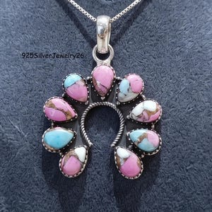 May include: A sterling silver horseshoe-shaped pendant featuring nine teardrop-shaped cabochons in shades of pink, white, and light blue with copper-coloured matrix veins. The pendant hangs from a silver chain and includes the text 925SilverJewelry26.