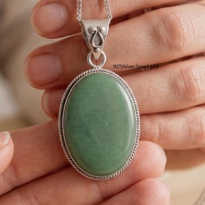May include: An oval green gemstone pendant set in a sterling silver frame with a twisted rope border. The pendant features a decorative silver bail with a scrollwork design and hangs from a silver chain. The text 925SilverJewelry26 is visible.
