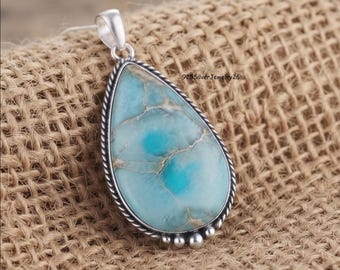 Puede incluir: Un colgante en forma de lágrima con una piedra azul claro con vetas blancas intrincadas. La piedra está engastada en un marco de plata pulida con un borde de cuerda trenzada y pequeñas esferas de plata en la base. El texto 925SilverJewelry26 es visible.