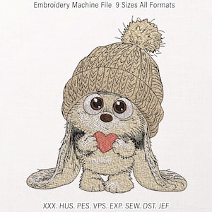 May include: Embroidery machine file featuring a fluffy creature wearing a tan knit beanie with a pom-pom, holding a small red heart. The text reads Embroidery Machine File 9 Sizes All Formats and lists file types XXX, HUS, PES, VPS, EXP, SEW, DST, JEF.