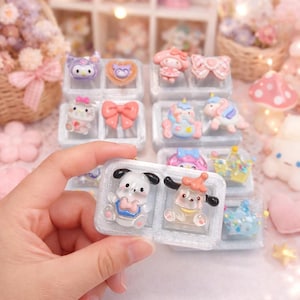 May include: A collection of colorful, miniature resin figurines in clear plastic cases. The figurines include cartoon characters, bows, and unicorns. The color palette is primarily pastel pink, blue, and purple. The figurines are displayed in a decorative setting.