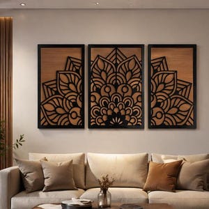 May include: Three-piece wall art set featuring intricate black mandala designs on a wooden background, framed in black. The artwork is displayed above a beige sofa with matching throw pillows, creating a cohesive and stylish living room aesthetic.