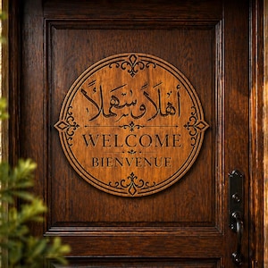 May include: A circular wooden sign with Arabic calligraphy and the words "WELCOME" and "BIENVENUE" in English and French. The sign is mounted on a dark brown wooden door with a black handle.