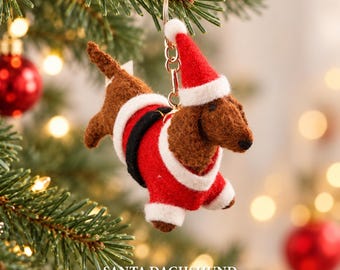 May include: A felt dachshund ornament wearing a red and white Santa suit and matching hat, attached to a gold-tone metal keychain. The ornament measures 5.5 inches in length. The text SANTA DACHSHUND 5.5in is printed at the bottom.