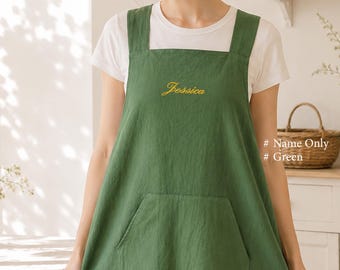 May include: A forest green apron featuring thick shoulder straps and a large front pocket. The name Jessica is embroidered in yellow cursive script on the chest. The apron is worn over a plain white short-sleeved t-shirt. Text on the right reads # Name Only # Green.