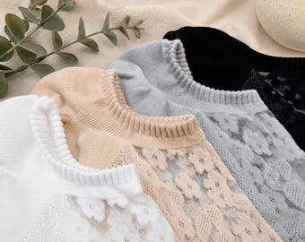 May include: Close-up of four pairs of no-show socks in white, beige, gray, and black. The white pair has a delicate lace design, while the beige and gray pairs feature floral lace patterns. The black pair has a subtle lace design. The socks are made of a soft, breathable material.