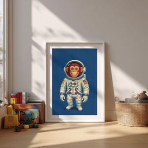 Peut inclure: Une affiche encadrée représentant un chimpanzé souriant dans une combinaison d'astronaute de style rétro sur fond bleu foncé. L'illustration a une esthétique vintage, avec le visage du singe et les détails de la combinaison bien mis en évidence. L'œuvre est dans un cadre blanc.