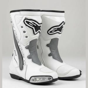 Puede incluir: Par de botas de moto blancas y negras. Las botas tienen un diseño alto, con exterior blanco, detalles en negro y una sección acolchada gris. Las botas presentan el logotipo de la marca en el lateral.