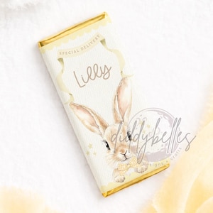 May include: A rectangular candy bar wrapper with a watercolor illustration of a bunny. The wrapper is cream-colored with gold accents and the text "Special Delivery" and "Lilly". The bunny has long ears and is wearing a yellow bow tie.