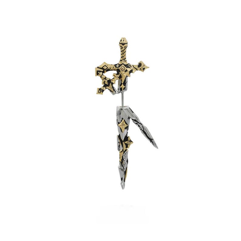 May include: A two-piece earring shaped like a sword, featuring a gold-toned hilt and crossguard with black accents, and a silver-toned blade section. The design includes intricate star-shaped engravings and a thin metal post connecting the two parts.