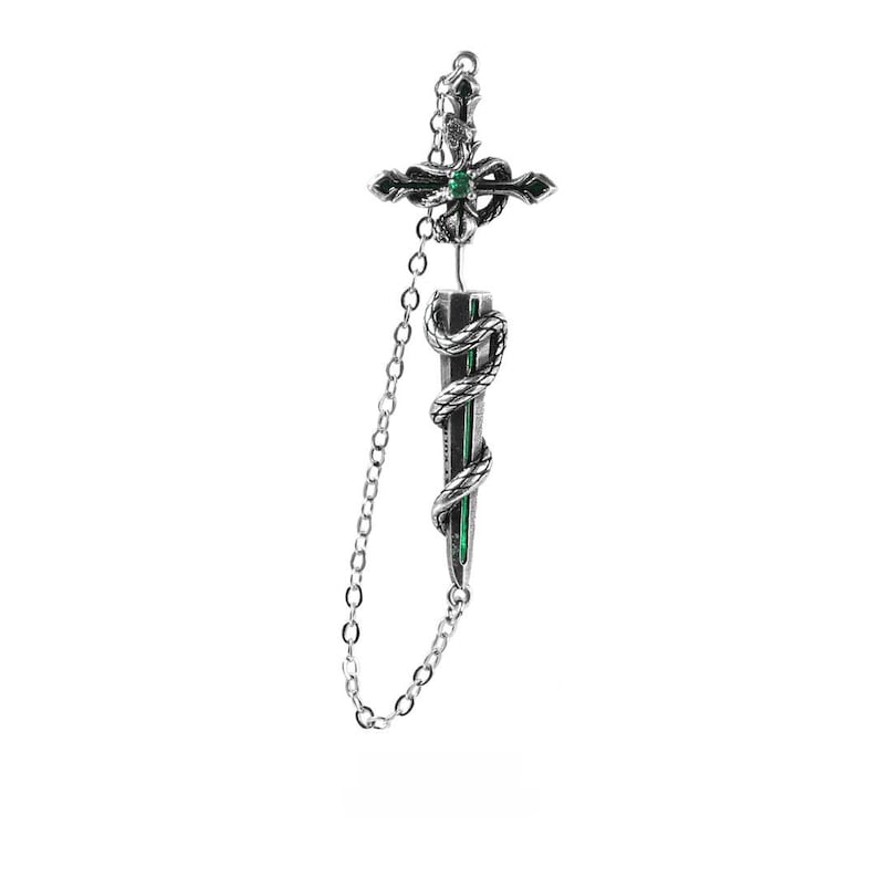 May include: A silver-toned metal earring featuring a cross-shaped top with a small green stone at the centre, connected by a delicate chain to a dagger-shaped pendant wrapped in a coiled snake, with a thin green vertical line along the blade.