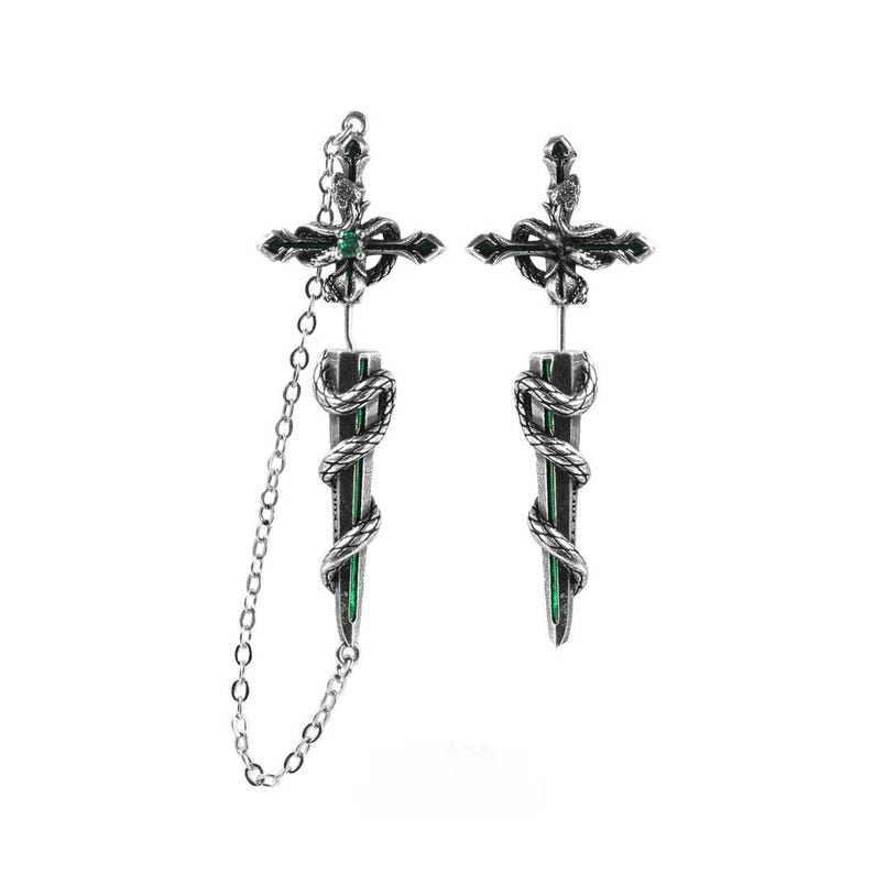 May include: A pair of silver-toned earrings featuring a sword and snake motif. The top section is a cross-shaped hilt with a small green stone, while the blade is wrapped in a coiled snake. One earring includes a delicate silver chain connector.