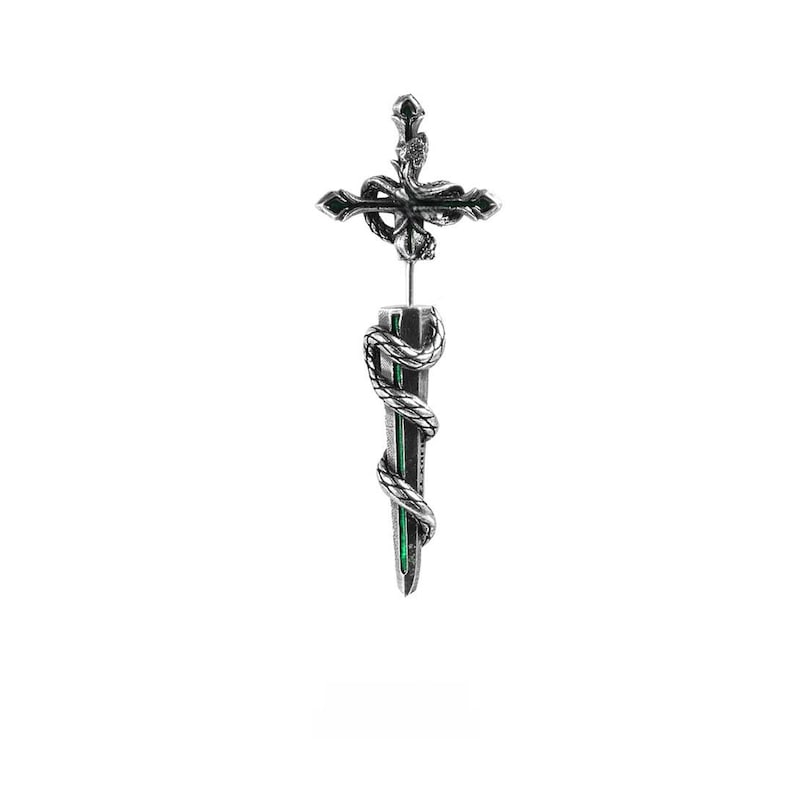 May include: A silver-toned earring featuring a cross at the top with a coiled snake design. Below the cross, a vertical bar is wrapped in a matching silver snake, revealing a vibrant green inlay along the centre of the metal structure.