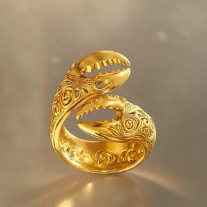 May include: A gold ring featuring a wrap-around design shaped like two crab claws. The surface of the ring is polished to a high shine and decorated with intricate, swirling engraved patterns that cover the entire band and the claw details.
