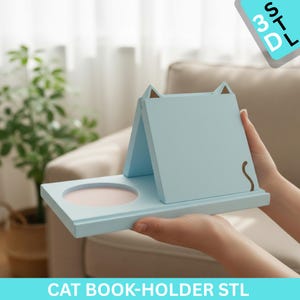 May include: A light blue cat-shaped book holder with a circular indentation and a brown tail design. The book holder has a cat ear design on top. The text "CAT BOOK-HOLDER STL" is at the bottom.