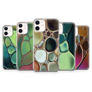 May include: A collection of five iPhone cases with abstract designs. Each case features a unique pattern of organic shapes in shades of green, brown, and gold, creating a fluid, bubble-like appearance. The cases are made of clear plastic, showcasing the phone's design.