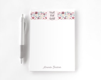 May include: A white notepad with a floral border at the top featuring the text Trust in the Lord with all your heart and the name Amanda Gardner at the bottom, accompanied by a white and gray retractable ballpoint pen.