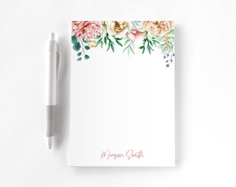 May include: A white notepad featuring a watercolor floral arrangement of pink and cream peonies with green leaves at the top and the name Morgan Smith printed in pink script at the bottom, accompanied by a white retractable pen.