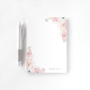 May include: A white ceramic mug with a black handle and the text "But First, Coffee" in a bold, black font. The mug is set against a blurred background, suggesting a cozy setting.