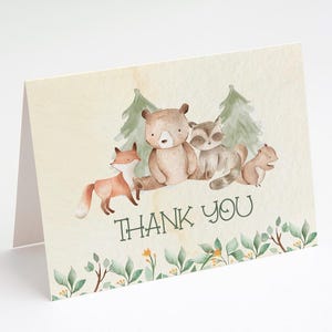 May include: Thank you card with a watercolor illustration of a bear, fox, raccoon, and squirrel in a forest setting. The card has a green and brown color scheme and the text "Thank You" in green.