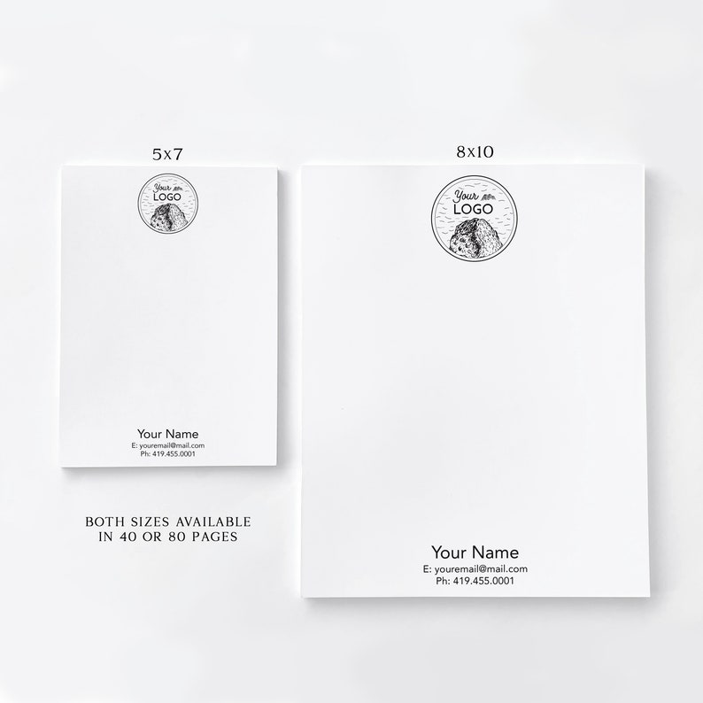 Op de afbeelding: Twee witte notitieblokontwerpen met een zwart-wit berglogo en de tekst "Your Logo" in een cirkel. De tekst "Your Name" staat onder het logo met contactgegevens. De notitieblokken zijn verkrijgbaar in twee formaten: 5x7 en 8x10. Beide formaten zijn verkrijgbaar in 40 of 80 pagina's.