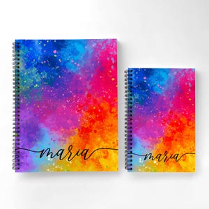 May include: Two spiral bound notebooks with a colorful watercolor design. The notebooks have the name "maria" written on them in black cursive.
