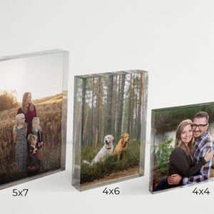 May include: Three acrylic photo blocks with different sizes and images. The largest block is 5x7 inches and shows a family with two children and two dogs in a field. The middle block is 4x6 inches and shows a forest scene with two dogs. The smallest block is 4x4 inches and shows a couple with their arms around each other in a forest setting.